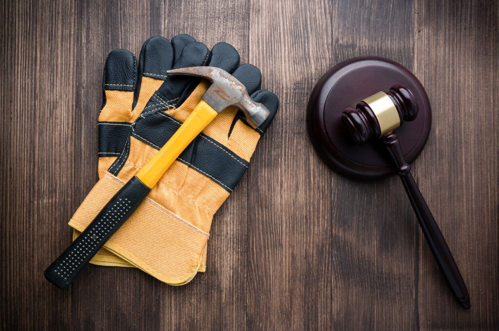 Workers gloves and hammer next to gavel on table
