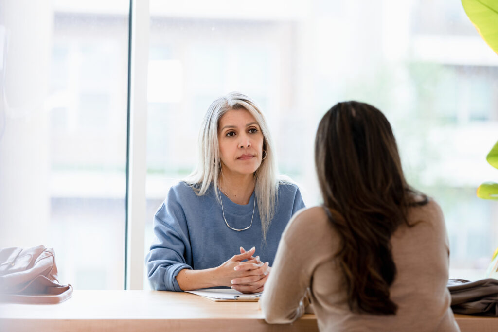 Serious businesswoman listens to unrecognizable female client