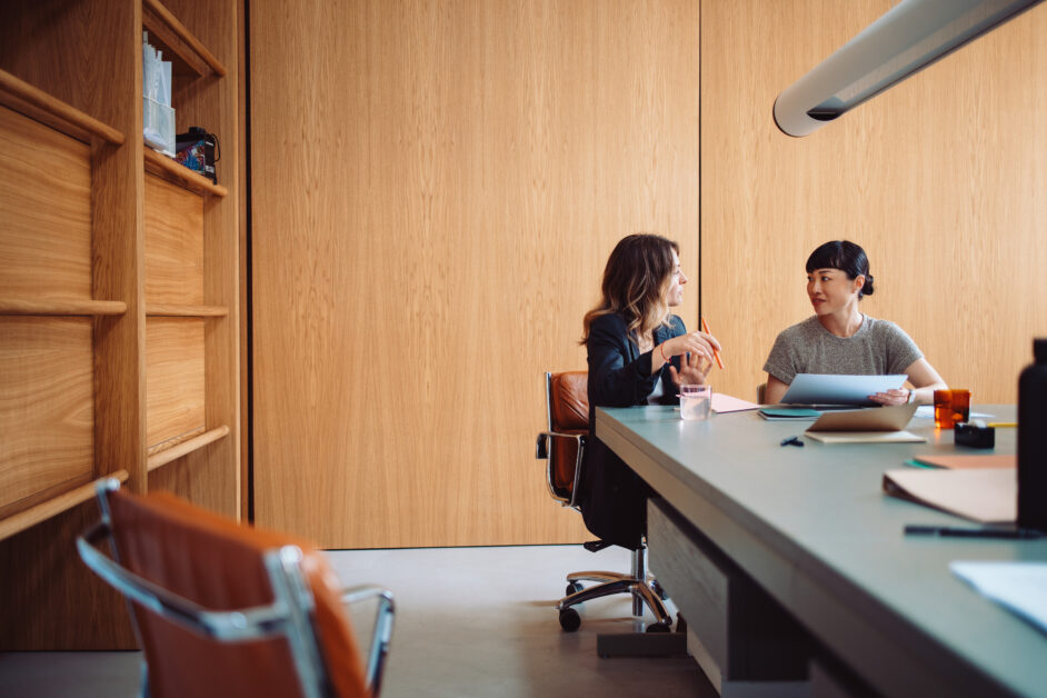 Coworkers sitting at a table together with computer discussing best case management platform