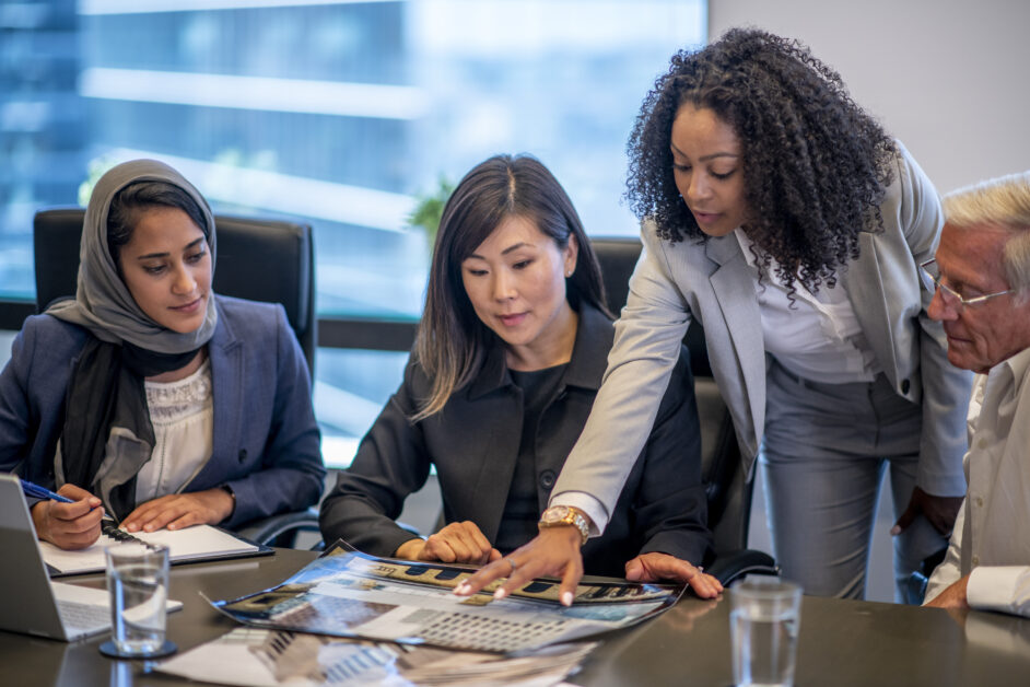Group of employees standing and sitting around the table discussing employee relations trends and employee relations metrics