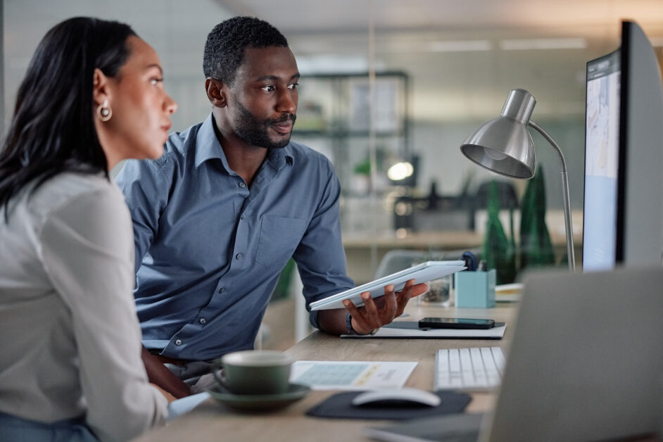 coworkers sitting at a desk in an office looking at investigation details using the best workplace investigations platform - hr acuity